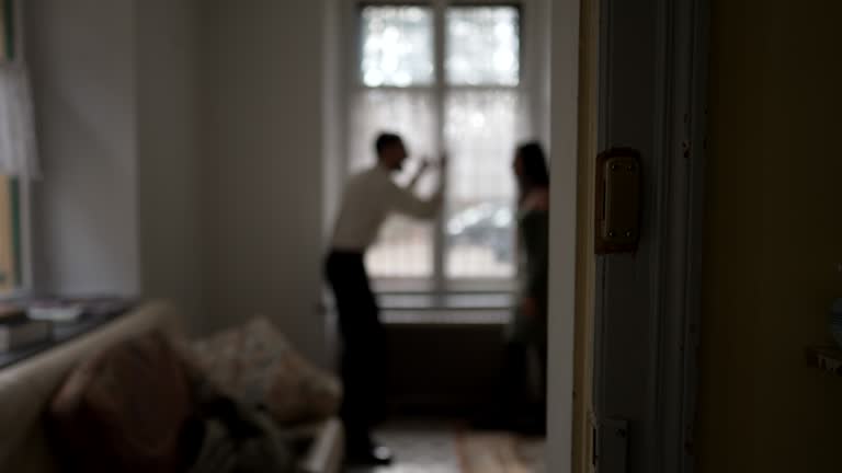 Blurred shot of couple arguing at home. Candid moment of husband and wife fighting each other. Person threatening the other in discussion