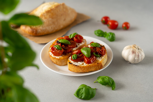 Bruschetta with Ricotto cheese and cherry Tomatoes, basil, garlic on a grey concrete background. Food. Food background