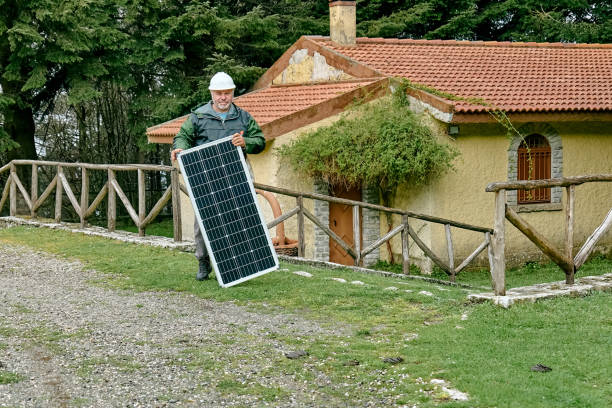 istock Middle aged bearded technician with voltaic solar panel near house in rural zone. Stand-alone photovoltaic solar panel system. Renewable ecological cheap green energy production. Energy independence. 1481968414