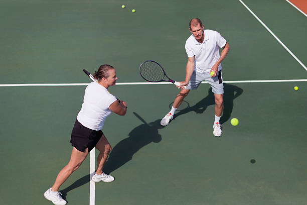 Older couple playing tennis on court  backhand stroke stock pictures, royalty-free photos & images