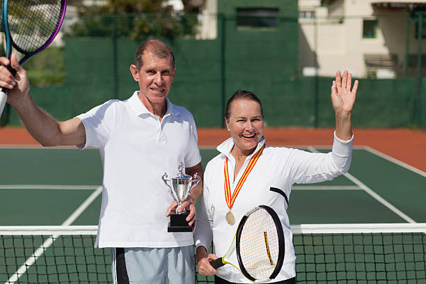 älteres paar mit trophäe auf den tennisplatz - tennis court love victory stock-fotos und bilder