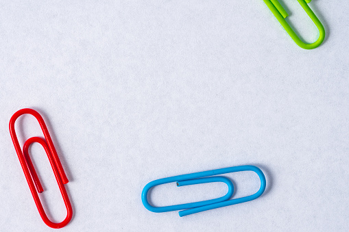 Colorful paper clips scattered on whit background. Studio shot