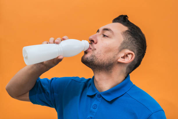 istock Handsome man drinks yogurt or milk on orange background. Mock up copy space 1481972296