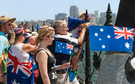 Sydney Australia - January 25 2011; Crowd of people on walkway edge to harbour hold flags celebrating Australia Day