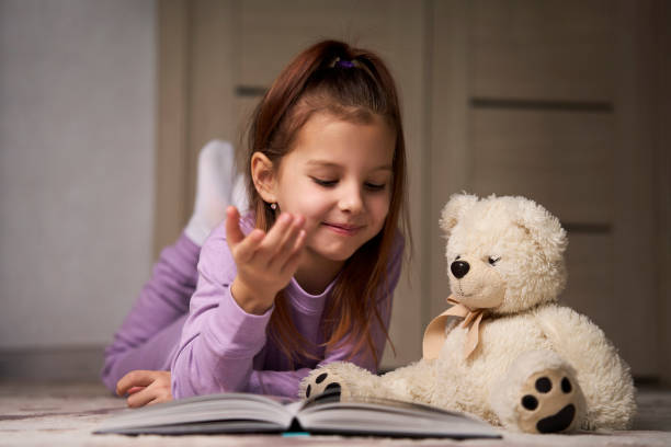 istock Cute girl lying on the floor and reading a book 1481976049
