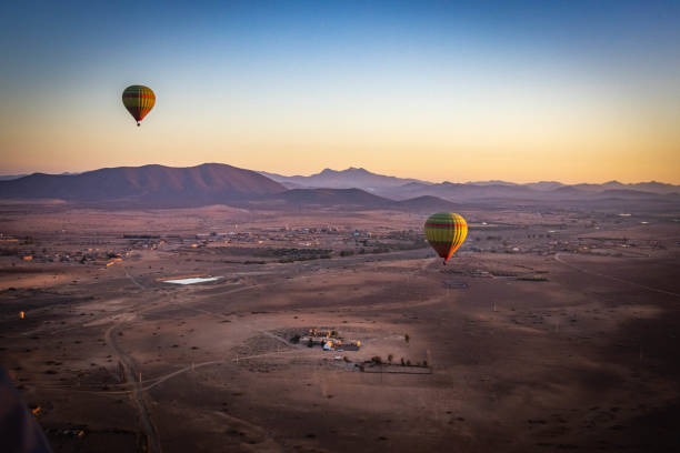 Tourist Hot Air Balloons over the Namib-Naukluft Nature Reserve Namibian Desert with sand dunes and pink coloured mountains and a dramatic early morning vibrant coloured sky in Namibia Africa