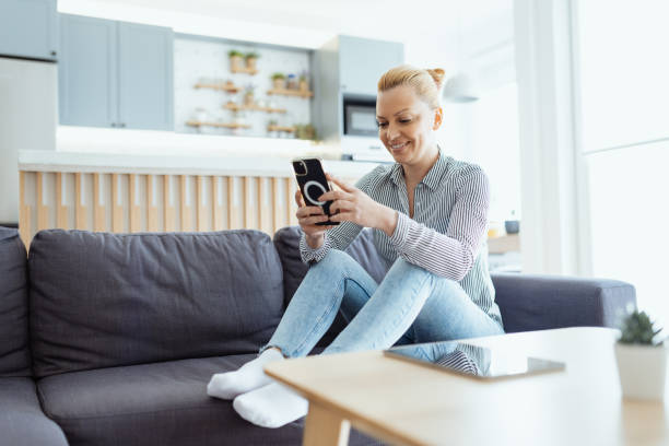 istock Mature woman enjoying time at home on the sofa with smart phone, using mobile app 1481982995