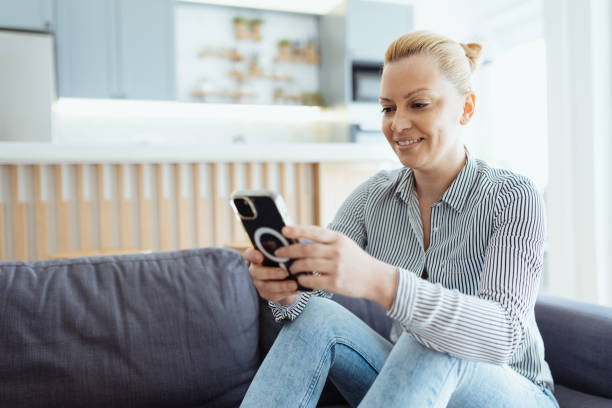 istock Mature woman enjoying time at home on the sofa with smart phone, using mobile app 1481982996