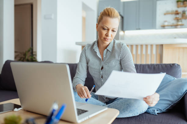 istock Mature entrepreneur working from home on laptop, anaylzing documents and doing paperwork 1481983524
