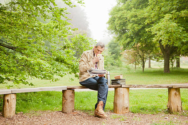 człowiek czytanie gazety w park - bench park bench park wood zdjęcia i obrazy z banku zdjęć