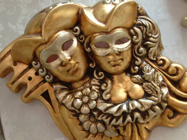 Gold and silver venetian festival mask. A souvenir mask depicts the face of a person, a harlequin of a theater satyr, jester or clown. Woman and man.