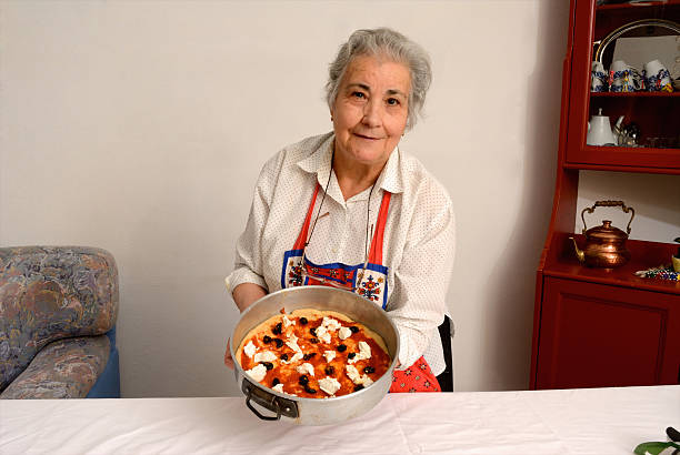 Older woman making pizza in living room  costantino stock pictures, royalty-free photos & images