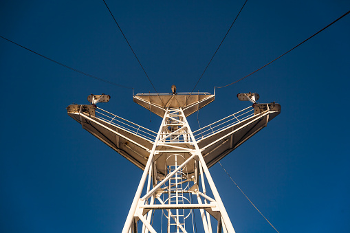 Steel tower with a high-voltage power line, against a blue sky.