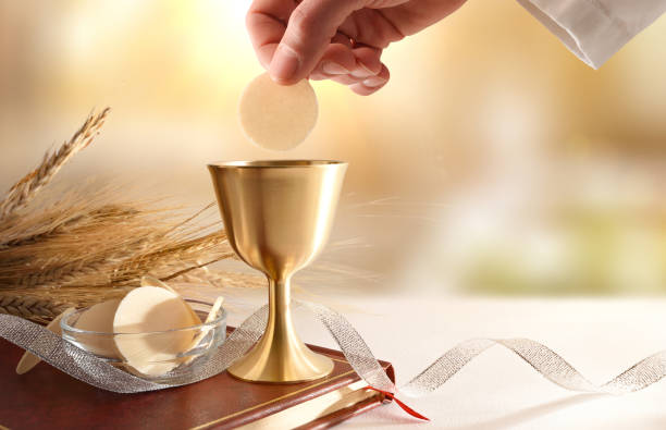 Priest dipping host in wine at Eucharist stock photo