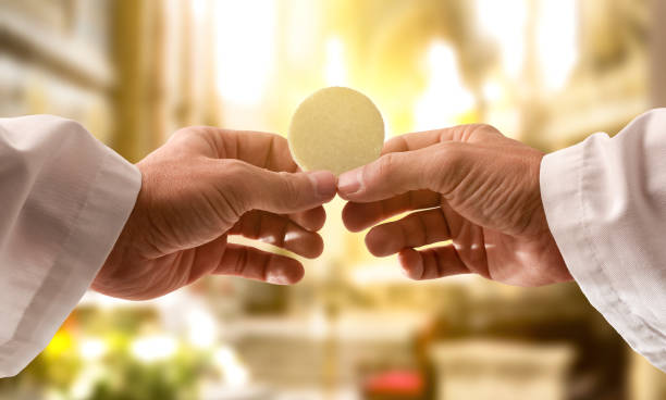 hands of a priest consecrating a host in the church - consecrated imagens e fotografias de stock