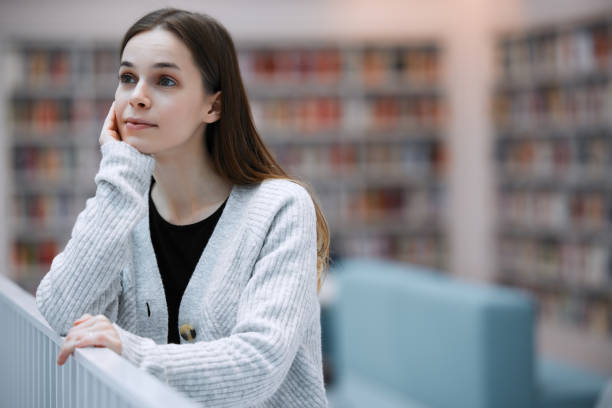 istock University, thinking and student in library for books,  knowledge and academic research for course. Education, college and young woman with ideas, vision and success mindset for future career goals 1482006375