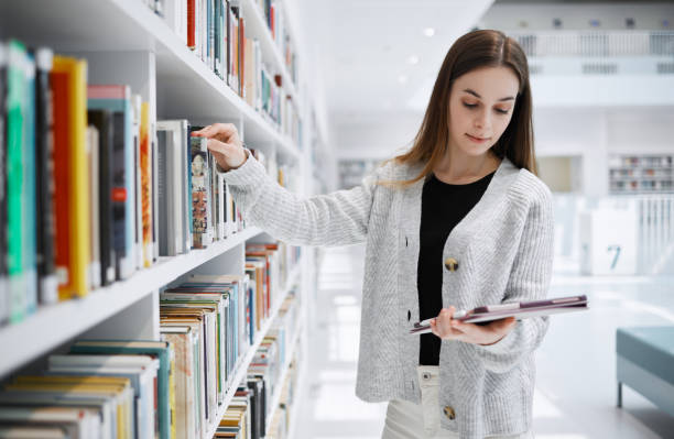 istock University, student or woman in library with tablet for research, education or learning. Bookshelf, books or girl on tech for scholarship research, search or planning school project at collage campus 1482006382