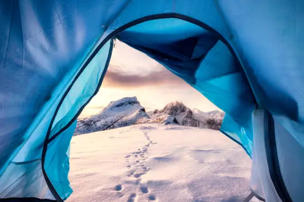 Photo of View from inside mountaineer tent of sunrise over snowy mountain peak on summit