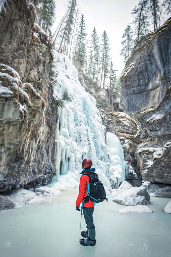 Mountaineer man standing in Maligne Canyon with frozen waterfall at Jasper national park, AB, Canada