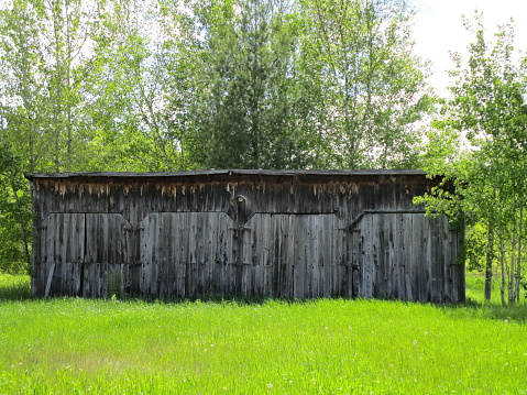 old abandoned wooden horse stable used as garage on farm
