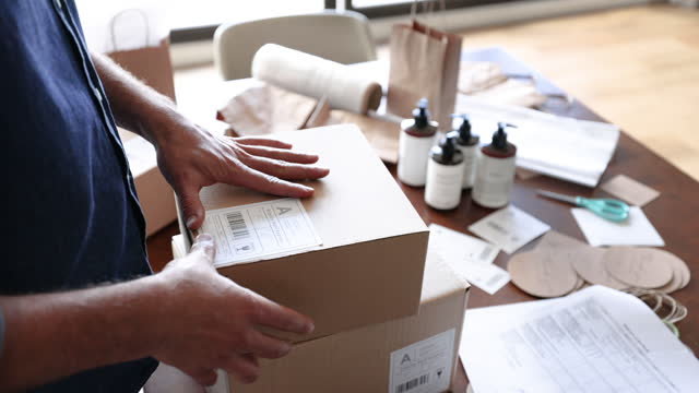 Close-up of a businessman working at home pasting a label to ship orders
