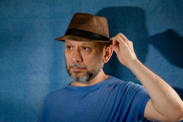 Portrait of a smiling bearded man wearing a hat. Isolated on blue background with shadow.