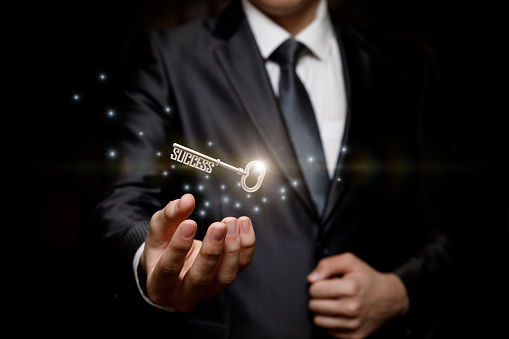 Businessman holding the key to success on a black background.