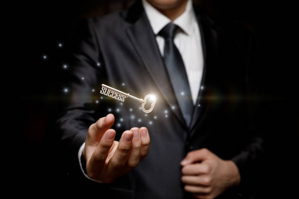 Businessman holding the key to success . Businessman holding the key to success on a black background. turnkey project stock pictures, royalty-free photos & images