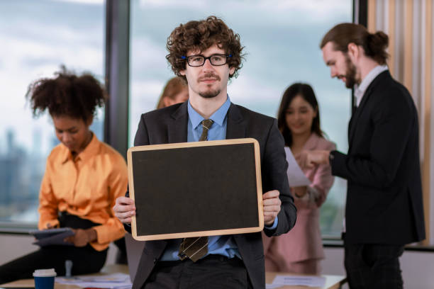 istock Handsome businessman  holding black board  in bright modern office 1482026948
