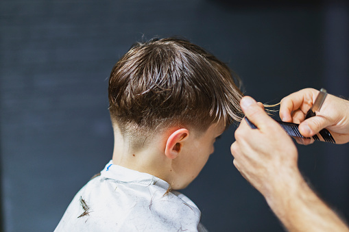 Closeup of a boy getting haircut at barber shop