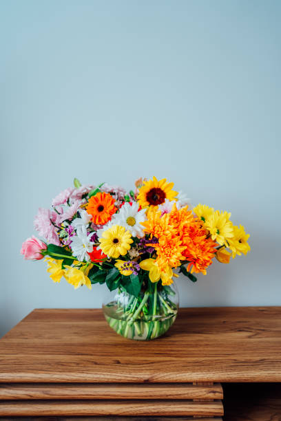istock Vase with huge multicolor various mixed flower bouquet on the wooden sideboard with light gray wall background. Giving flowers. Mother's day, women day, valentine's day, birthday gift. Vertical card. 1482037447