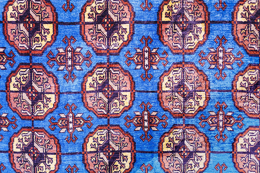 Colorful handmade silk carpet with pattern in red tones, traditional uzbekistan style. Close up.