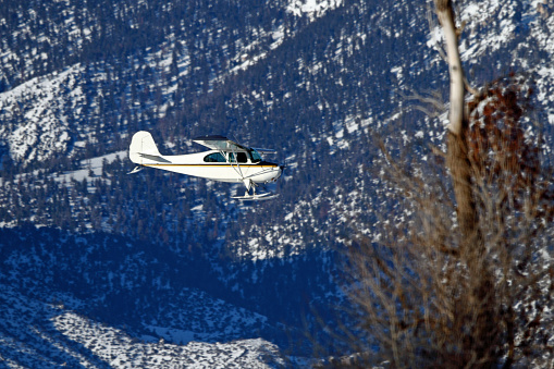 Old classic airplane on snow covered airfield. Abandoned vintage biplane in sunny winter day with clear sky after snowfall