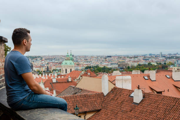 istock A young man sitting in front of Prague tiled roofs. Czech 1482051046