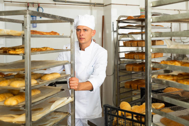 istock man in chefs uniform rolling trolley with bread in bakery 1482067831