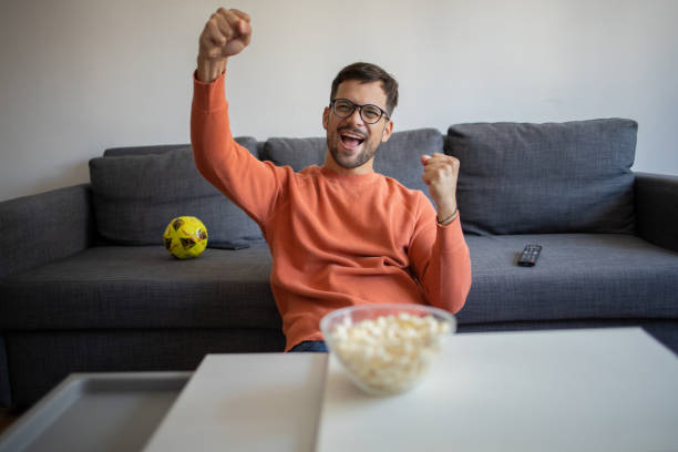istock Excited man cheering while watching tv at home 1482071518