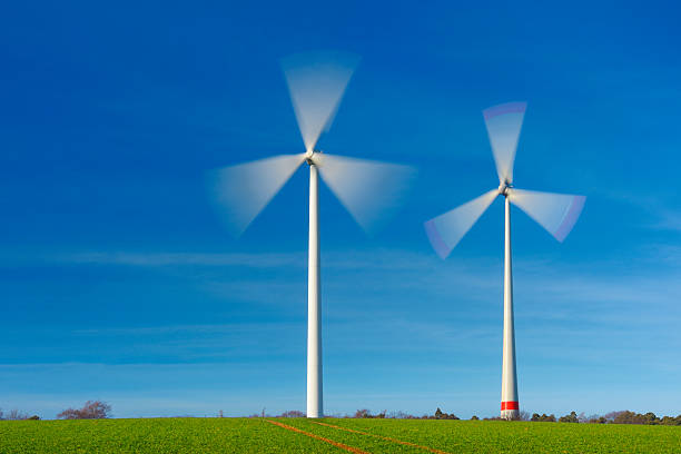 Two wind turbines in movement on a green field