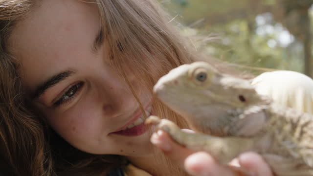 nature girl holding iguana at zoo enjoying excursion to wildlife sanctuary student having fun learning about reptiles 4k