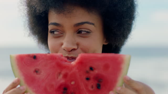 beautiful woman eating watermelon on beach enjoying delicious juicy fruit smiling happy female having fun summertime by the sea 4k footage