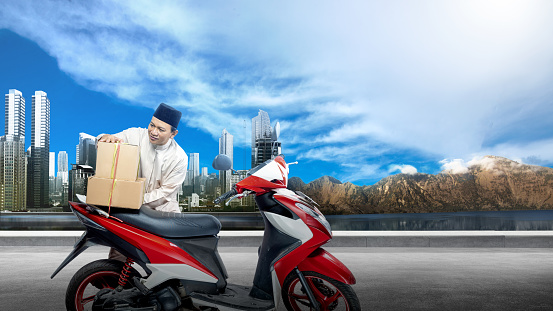 Asian Muslim man tying box on motorcycle prepare for mudik on the street