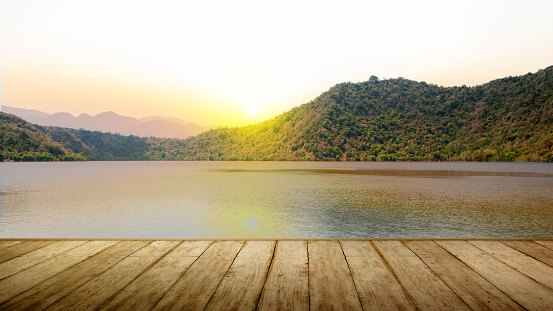 Wooden floor with the landscape of a lake with sunset sky background