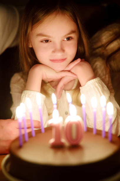 linda niña de diez años pidiendo un deseo antes de soplar velas en su pastel de cumpleaños. niña celebrando su cumpleaños. - celebration 10 11 years birthday cake cake fotografías e imágenes de stock