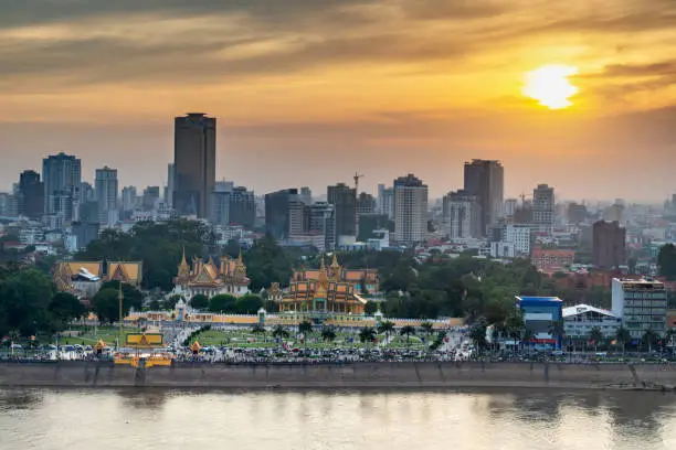 The golden sun hangs over Cambodia's capital city and it's busy Riverside area and famous landmark,the Royal Palace,reflecting sunlight from the calm waters of Tonle Sap river.