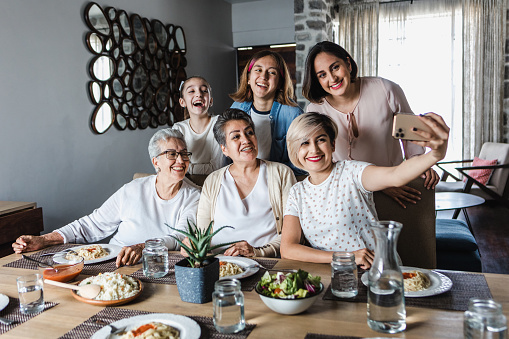 latin Multi Generation women Family Posing For photo Selfie at dinner time At Home Together in Latin America