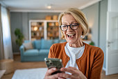 Mature woman using smart phone at home