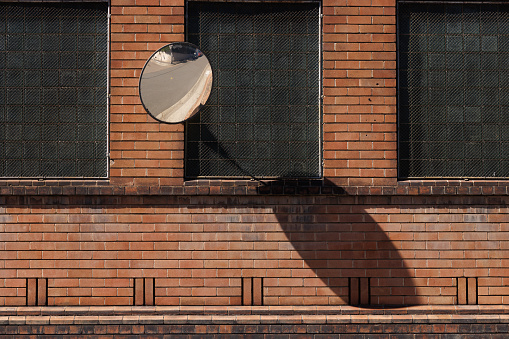 Curved traffic mirror on a brick wall.