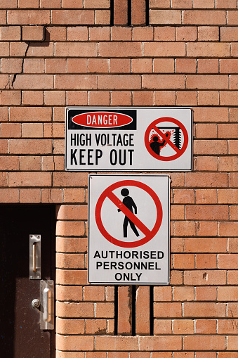 Danger, high voltage, keep out sign on a brick wall.