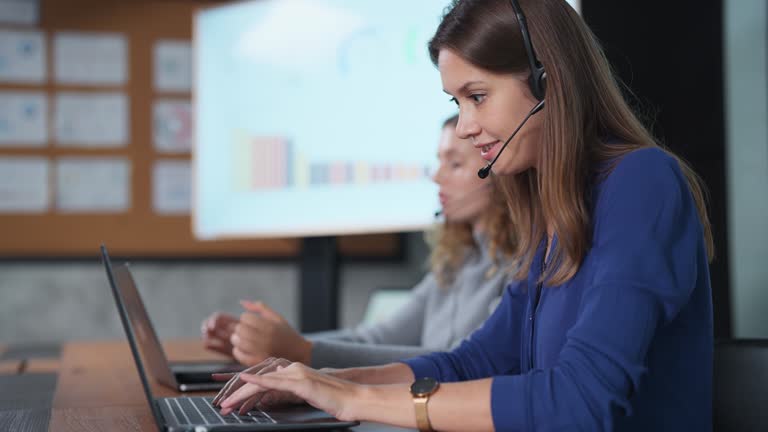 Solving problems for customers quickly makes customers impressed and come back to use the service again. Technician woman agent with headsets touching the microphone and talk to customer using computer in the call center room.