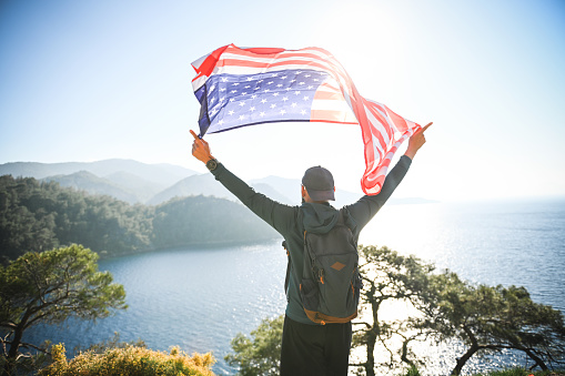 man with american flag on the background of the sea and mountains