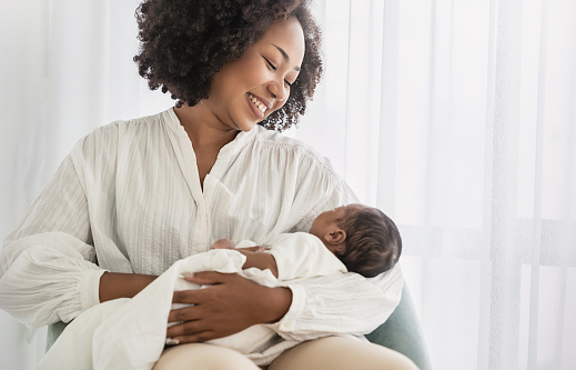 Close up portrait of beautiful young African American  mother holding sleep newborn baby in hospital bed room. Healthcare medical love black afro woman lifestyle mother's day, breast with copy space.